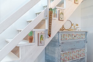 A staircase with white railings, a blue dresser with floral patterns, and a framed picture on the wall. - Grandma's House with Wi-Fi and Air Conditioning (Syracuse)