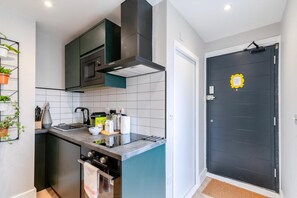 A modern kitchen with a built-in oven, a microwave, and a stainless steel range hood. - The Balham Hideaway (London)