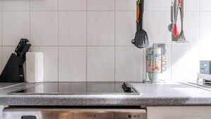 Cozinha com fogão embutido, suporte para facas e conjunto de utensílios de cozinha na parede.