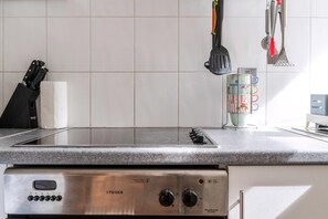 A kitchen with a built-in stove, a knife block, and a set of kitchen utensils on the wall. - Gorgeous Putney Flat (London)
