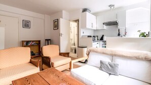 Um espaço compacto com cozinha compacta, sofá, mesa de jantar e estante.