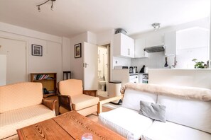 A compact living space with a kitchenette, a sofa, a dining table, and a bookshelf. - Gorgeous Putney Flat (London)