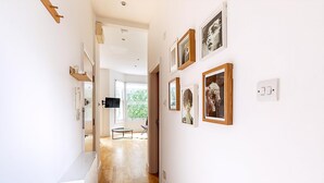 A hallway with a wooden floor, white walls, and framed pictures. - Contemporary Archway Retreat Near Tube (London)