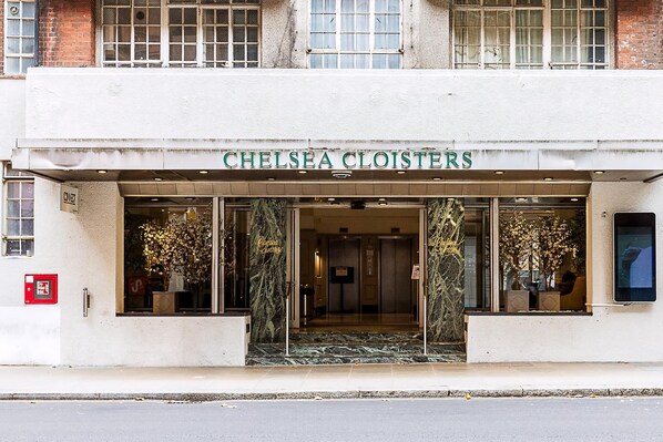 A hotel entrance with a sign reading 'CHELSEA CLOISTERS,' a marble entrance, and a fire alarm box. - Stylish Chelsea Flat Near Sloane Square (London)