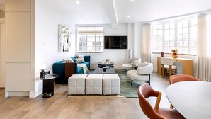 Una sala de estar moderna con sofá, mesa de centro, reposapiés y un comedor con sillas y mesa.