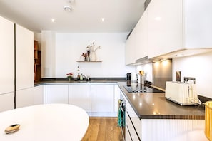 Eine moderne Küche mit weißen Schränken, einer Arbeitsplatte, einem Toaster und einem Regal mit Dekoration.