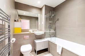 Ein modernes Badezimmer mit einer gläsernen Duschkabine, einem weißen Waschbecken und einer Toilette.