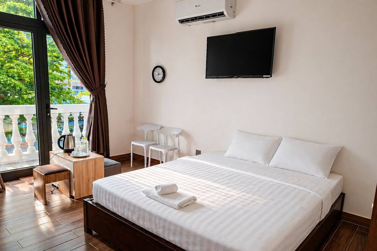 Habitación de hotel con una cama grande, televisión, reloj y balcón con vistas.