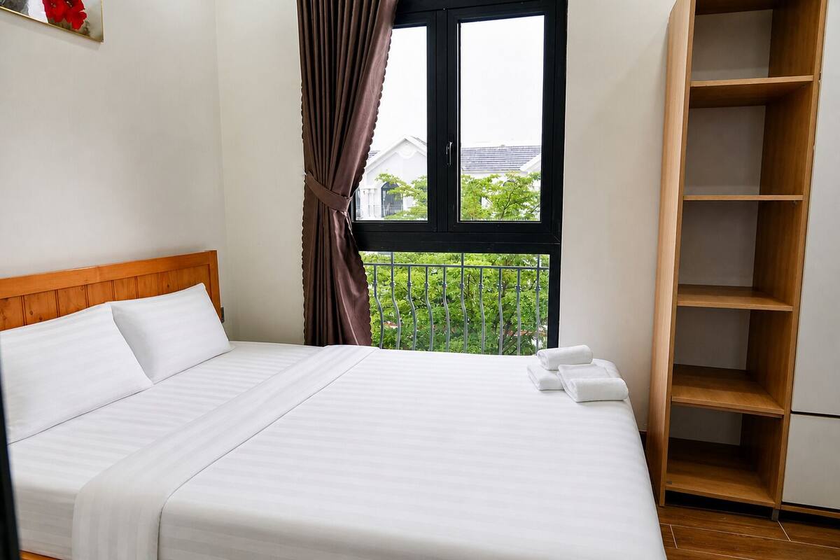 Un dormitorio con cama, ventana con cortinas, balcón y un armario de madera.