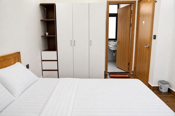 Un dormitorio con cama, armario, estantería y puerta abierta al baño.