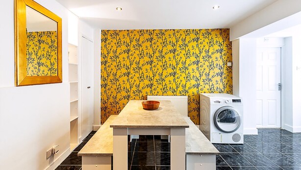Une petite cuisine équipée d’un lave-linge, d’un évier et d’un miroir mural.