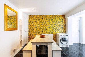 A compact kitchen with a washing machine, a sink, and a mirror on the wall. - Stylish Earl's Court Getaway (London)