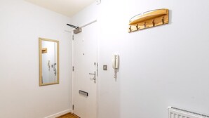 Ein Zimmer mit Holzboden, einer weißen Tür, einem Spiegel, einem Lichtschalter und einer Heizung.