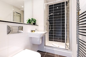 A modern bathroom with a glass-enclosed shower, a white sink, and a large mirror. - Modern Mile End Flat With Balcony Terrace (London)