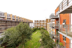 A multi-story residential building with balconies, a central courtyard, and a mix of brick and modern architecture. - Modern Mile End Flat With Balcony Terrace (London)