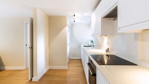Una cucina moderna con mobili bianchi, un piano di lavoro nero e un pavimento in legno.