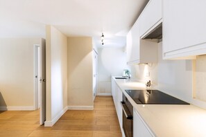 Eine moderne Küche mit weißen Schränken, einer schwarzen Arbeitsplatte und Holzboden.