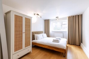 Quarto com cama, guarda-roupa e janela com cortinas.
