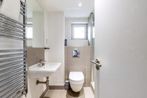 A bathroom with a sink, toilet, and shower area. - Belgravia Living 2-bed, 1-bath Apartment With Balcony (London)