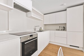 Eine moderne Küche mit weißen Schränken, einem Backofen, einer Spüle und einem Wasserkocher.