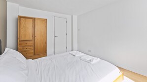Quarto com cama, guarda-roupa de madeira e uma porta.