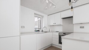 Une cuisine moderne avec des meubles blancs, une fenêtre et un lave-vaisselle encastré.