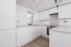 Eine moderne Küche mit weißen Schränken, einem Fenster und einem eingebauten Geschirrspüler.
