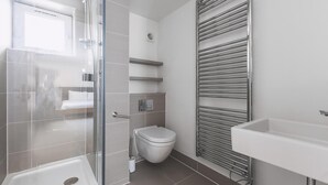 Une salle de bain moderne avec une douche à parois de verre, des toilettes, un lavabo et un porte-serviettes.