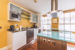 Eine moderne Küche mit eingebauter Mikrowelle, Glastrensen, einer Kaffeemaschine und einem großen Fenster.
