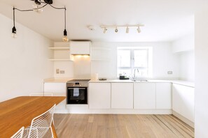 Eine moderne Küche mit weißen Schränken, einem Holztisch und Pendelleuchten.