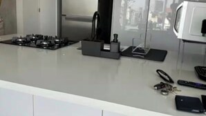 Une cuisine moderne équipée d’une cuisinière à gaz, d’un four à micro-ondes et offrant une vue sur la ville par la fenêtre.
