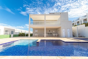 Um edifício moderno com piscina, área de estar externa e céu limpo.