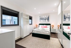Ein modernes Schlafzimmer mit einem großen Bett, Nachttischen, einem Kleiderschrank und einem Fenster mit Blick.