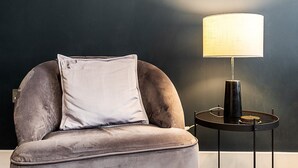 Une chaise avec un coussin et une table avec une lampe.