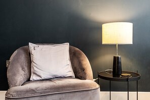 Ein Stuhl mit Kissen und ein Tisch mit Lampe.