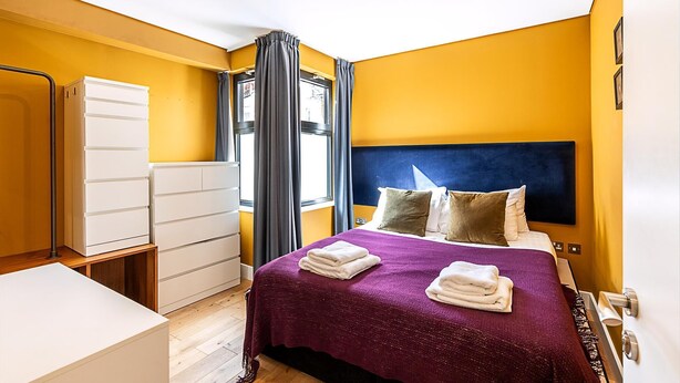 Une chambre d’hôtel avec un lit, une armoire, un bureau et une fenêtre avec des rideaux.
