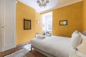 Ein Schlafzimmer mit Bett, Fenster, Tür und einer Chandelier.