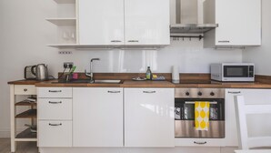 Eine moderne Küche mit weißen Schränken, einer Holz Arbeitsplatte, einem Edelstahlbackofen und einer Mikrowelle.