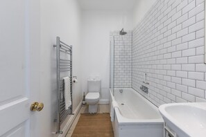 A bathroom with a white toilet, a bathtub, and a shower. - Stylish West London Stay by Hammersmith (London)