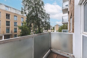 Ein Wohnbalkon mit Blick auf benachbarte Gebäude und einen Baum.