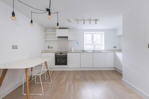 Eine moderne Küche mit weißen Schränken, einem eingebauten Backofen und einem Essbereich mit weißem Tisch und Stühlen.