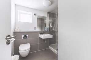 Ein modernes Badezimmer mit Toilette, Waschbecken und Dusche.