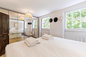 Ett hotellrum med en stor säng, en spegel, ett fönster med utsikt över grönområden och en dörr.