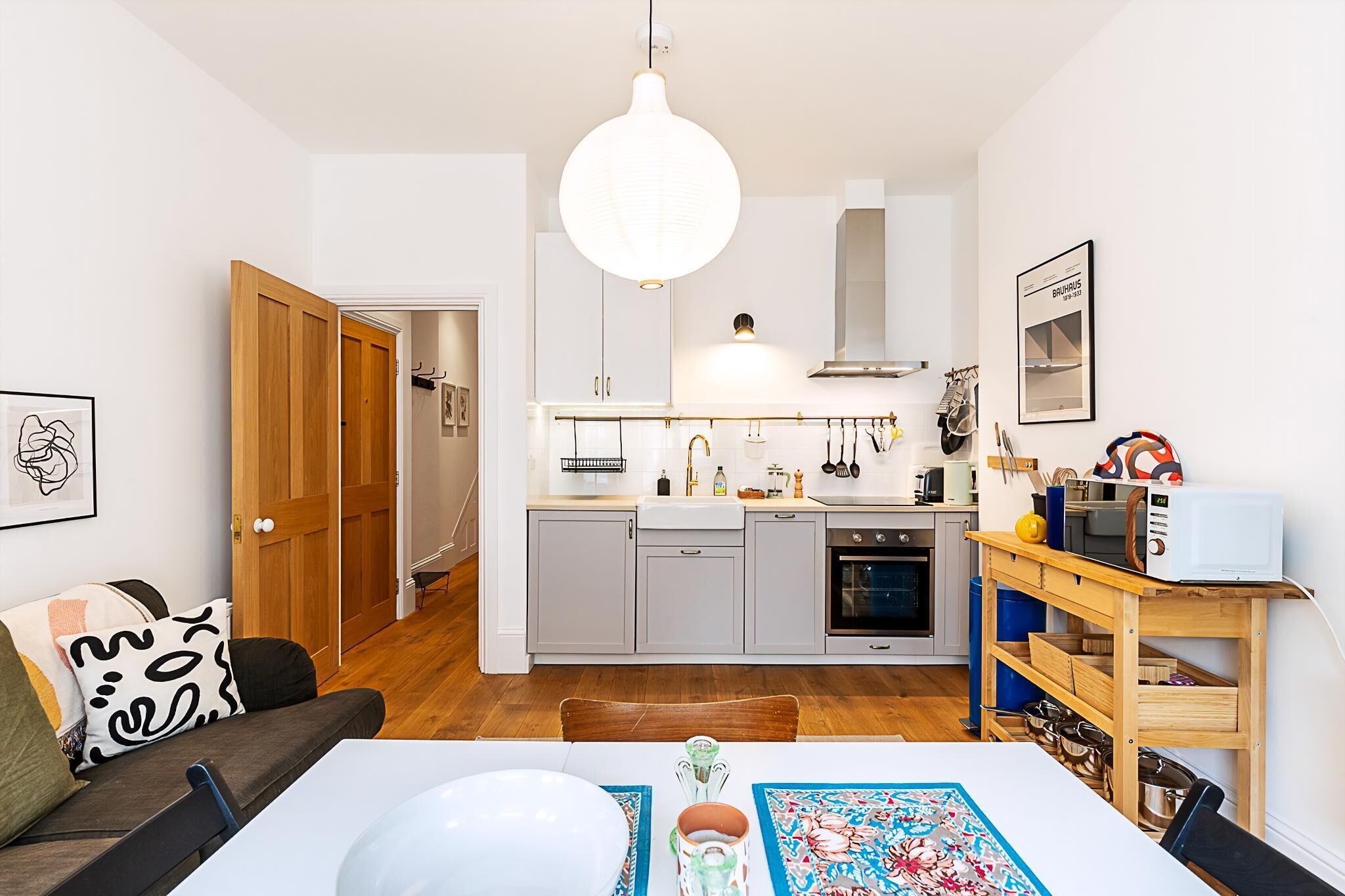 A compact kitchen with a central island, a dining area with a table and chairs, and a wooden door leading to another room.