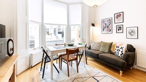 Una sala de estar luminosa con una mesa de comedor, sofá y ventanas amplias.