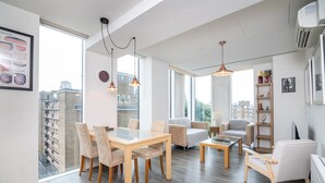 Ein modernes Wohnzimmer mit Essbereich, großen Fenstern und Blick auf die Stadt.