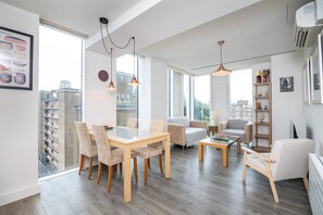 Ein modernes Wohnzimmer mit Essbereich, großen Fenstern und Blick auf die Stadt.