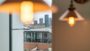 Blick aus einem Fenster auf eine Stadtlandschaft, darunter Hochhäuser und ein Baukran.