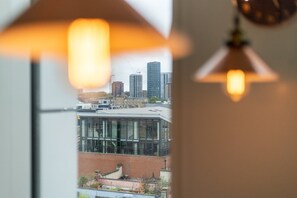 Blick durch ein Fenster auf ein modernes Gebäude und hohe Wohnhäuser im Hintergrund.