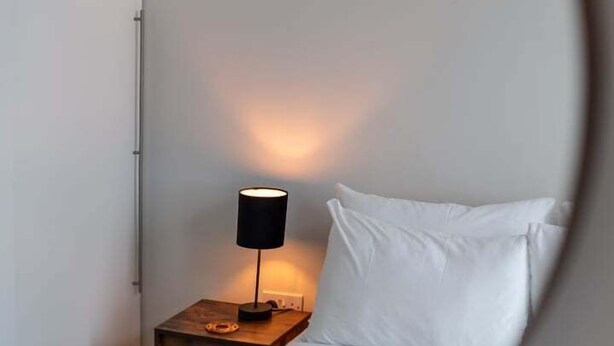 Ein Schlafzimmer mit einem Bett, einem Nachttisch und einer Lampe.